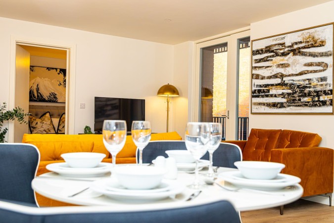 Airbnb dining table set with cups, glasses and cutlery.