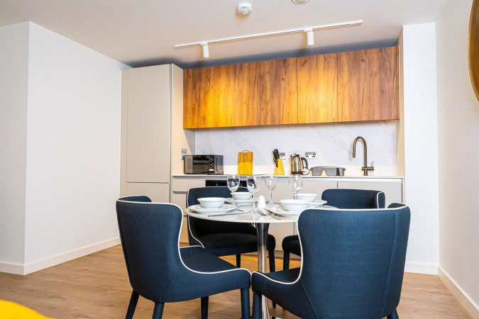 Airbnb dining area with kitchen visible in the background.
