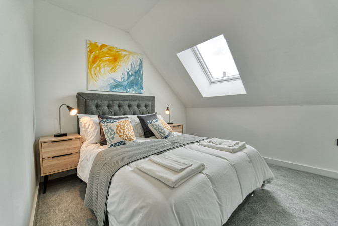 Airbnb bedroom with skyline view through large window.