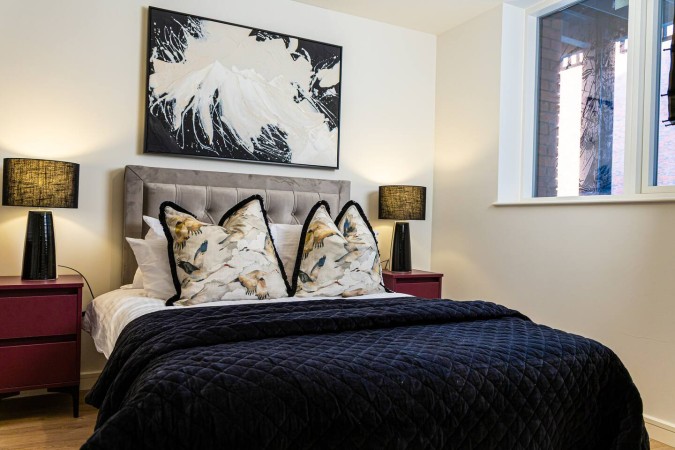 Luxury Airbnb bedroom with neatly made bed, decorative cushions and bedside lamps.
