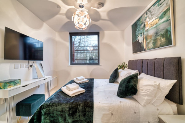 Stylish Airbnb bedroom with comfortable bed, window view and modern TV.